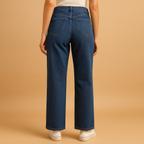 Sienna high-waisted loose fit jeans in dark blue denim seen from the back, worn with cream trainers